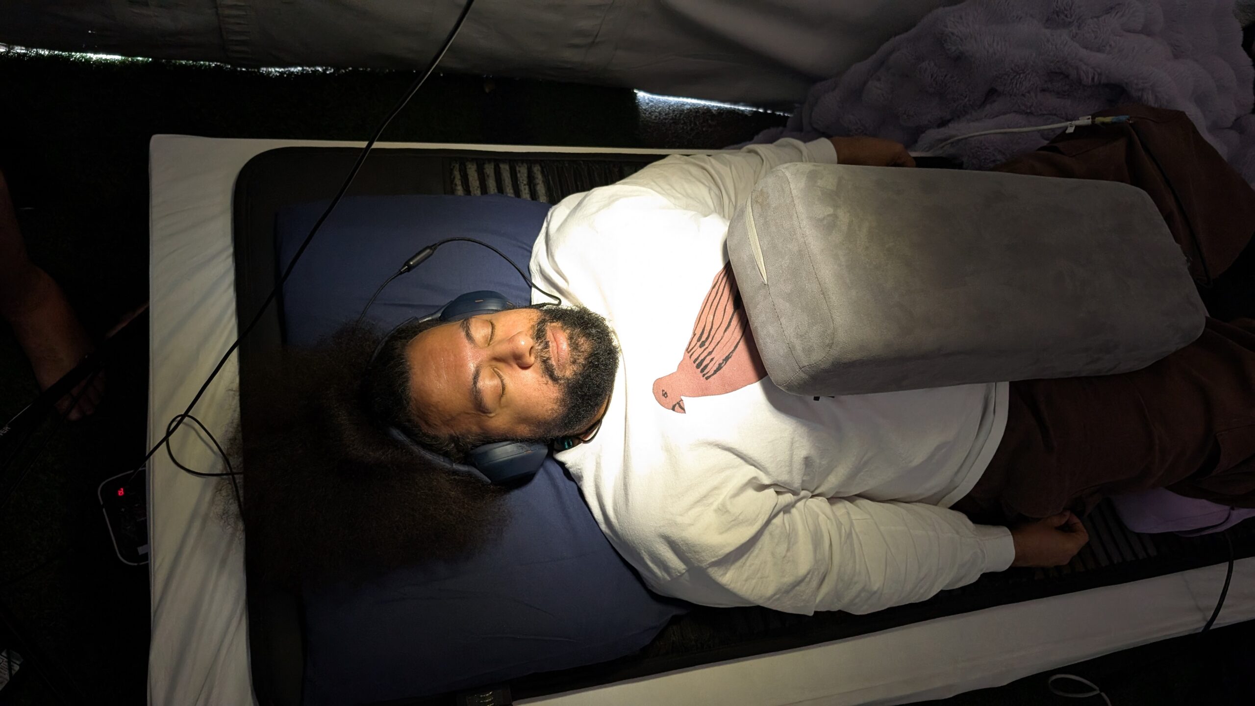 Reggie Watts lying on a VAVE™ bed experiencing a Multisensory Resonant Frequency Therapy session inside the PORTAL Dome at the MAPS Psychedelic Science Conference.