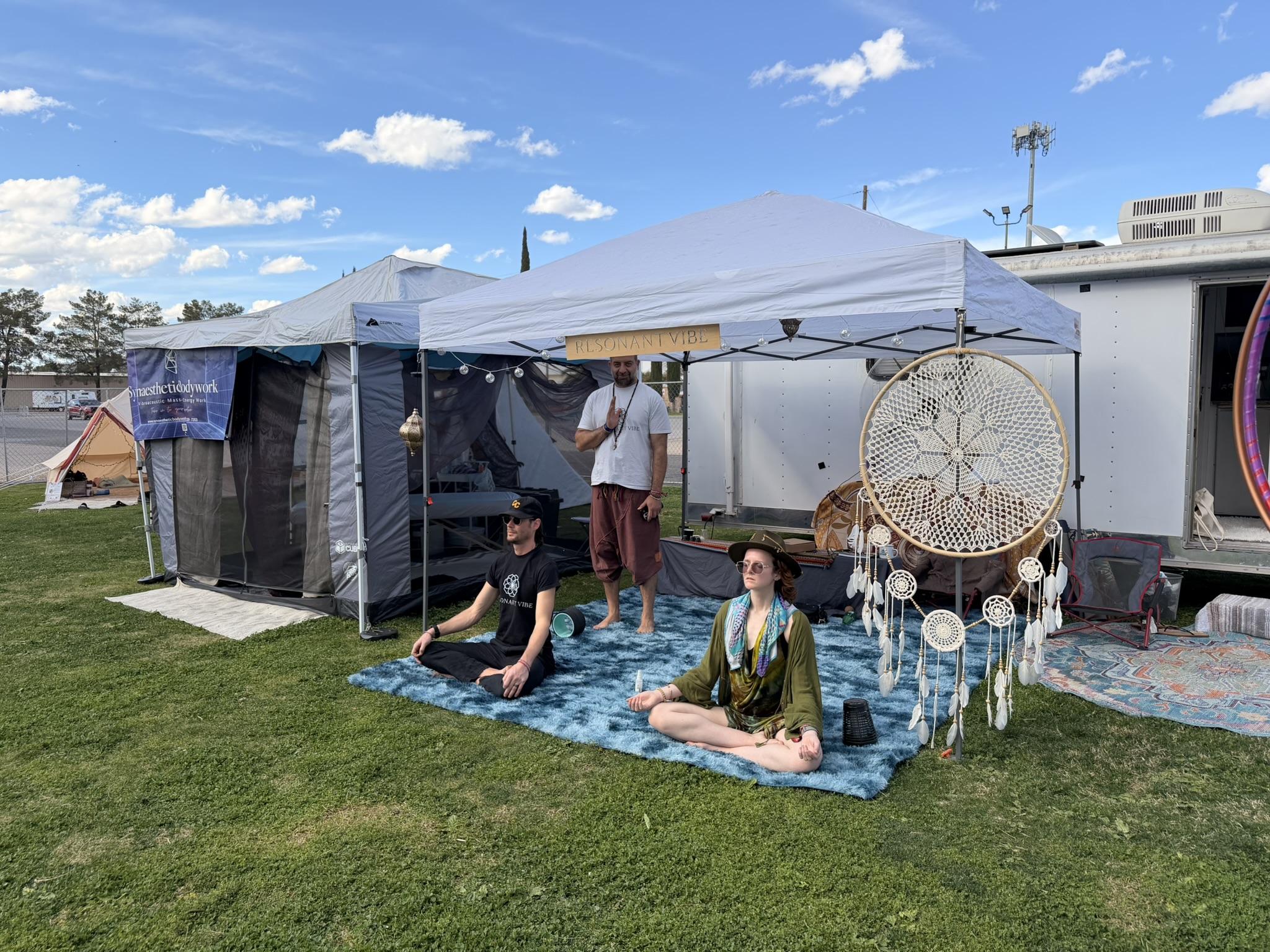 Members of the ResonantVibe team sitting in meditation outside their VAVE™ setup in the Topaz Healing Sanctuary at Gem & Jam Festival 2026.